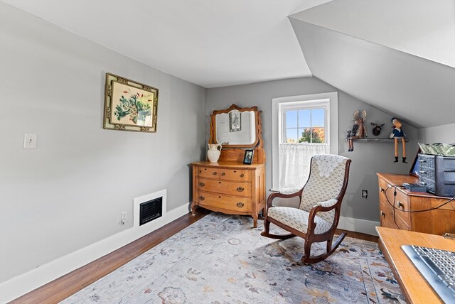 sitting room with hardwood / wood-style floors and vaulted ceiling