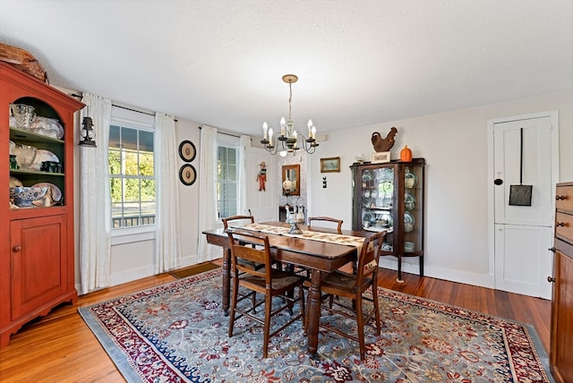 dining room featuring a textured ceiling, an inviting chandelier, and hardwood / wood-style floors