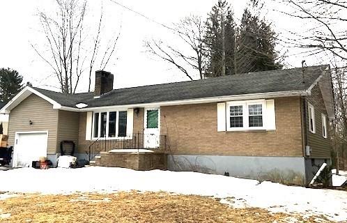 single story home with a garage, brick siding, and a chimney