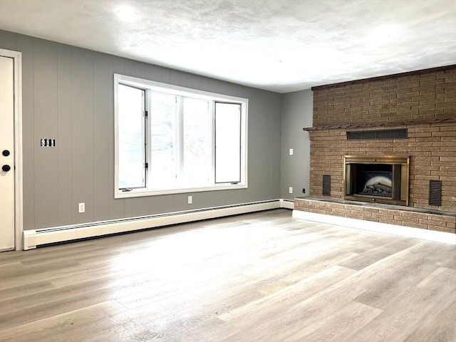 unfurnished living room featuring a baseboard heating unit, a brick fireplace, visible vents, and wood finished floors