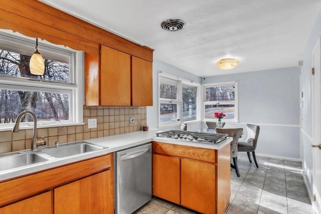 kitchen with kitchen peninsula, appliances with stainless steel finishes, decorative backsplash, plenty of natural light, and sink