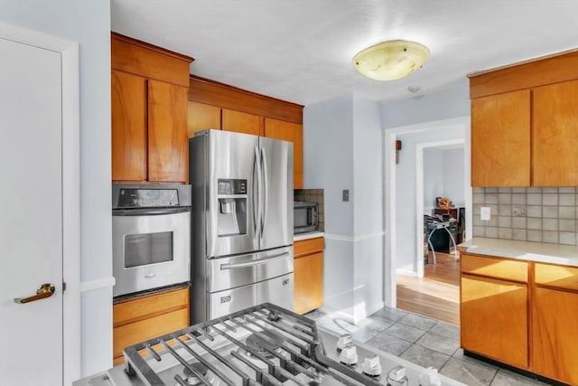 kitchen featuring light tile patterned floors, backsplash, and stainless steel appliances