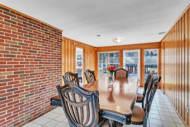 dining space with brick wall, light tile patterned floors, and wooden walls