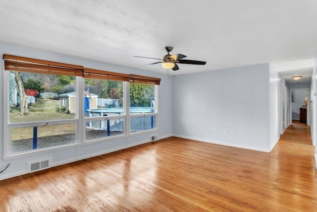 empty room featuring light hardwood / wood-style floors, ceiling fan, and a healthy amount of sunlight