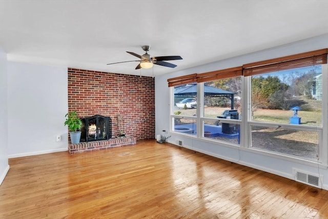 unfurnished living room with ceiling fan, a fireplace, and light hardwood / wood-style floors