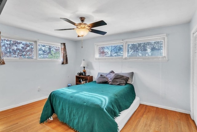 bedroom featuring ceiling fan, multiple windows, and hardwood / wood-style floors