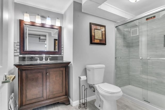 bathroom featuring toilet, vanity, decorative backsplash, and a shower with shower door