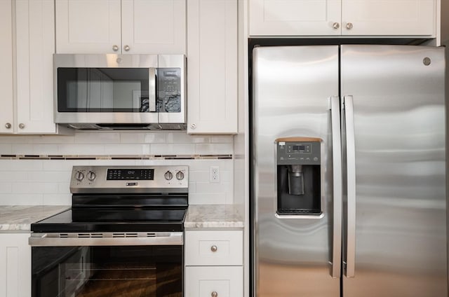 kitchen with white cabinetry, appliances with stainless steel finishes, light stone counters, and decorative backsplash