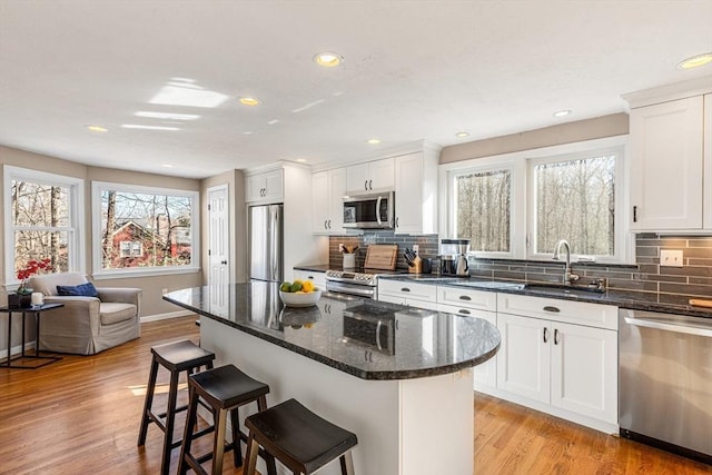 kitchen featuring a sink, light wood-style floors, appliances with stainless steel finishes, and a breakfast bar area