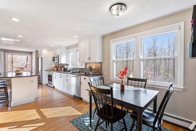 dining room with light wood-style flooring, recessed lighting, and a baseboard radiator