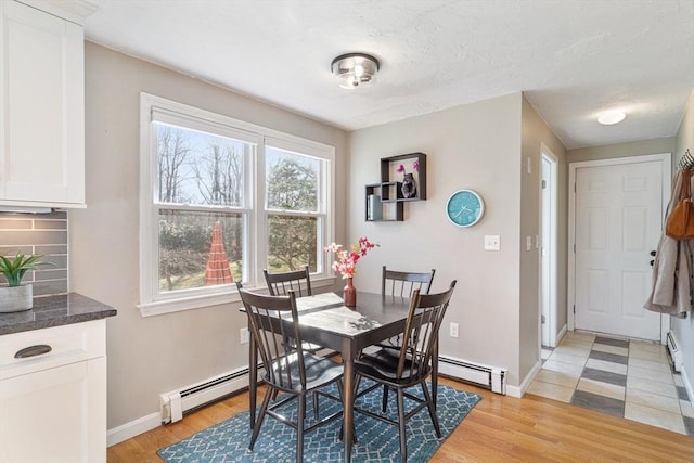 dining area with light wood-type flooring, baseboards, and baseboard heating