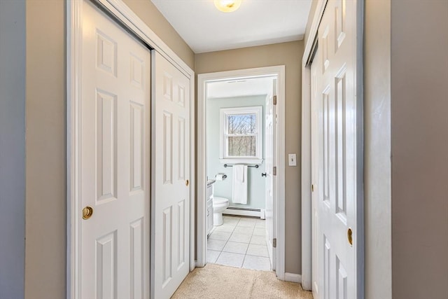 hall featuring light tile patterned flooring, light colored carpet, and a baseboard radiator