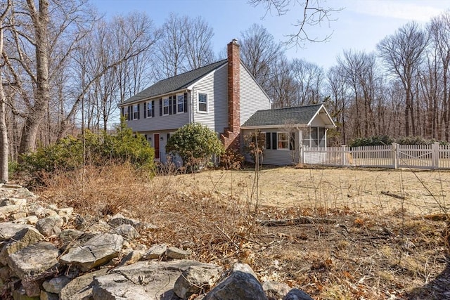 view of property exterior featuring a gate, fence, a sunroom, and a chimney