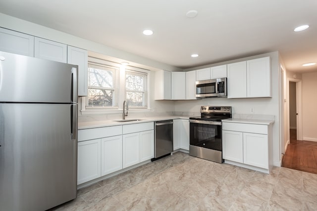 kitchen with white cabinets, light wood-type flooring, stainless steel appliances, and sink