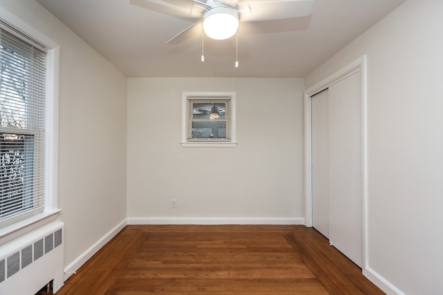 unfurnished bedroom featuring hardwood / wood-style floors, a closet, radiator, and ceiling fan