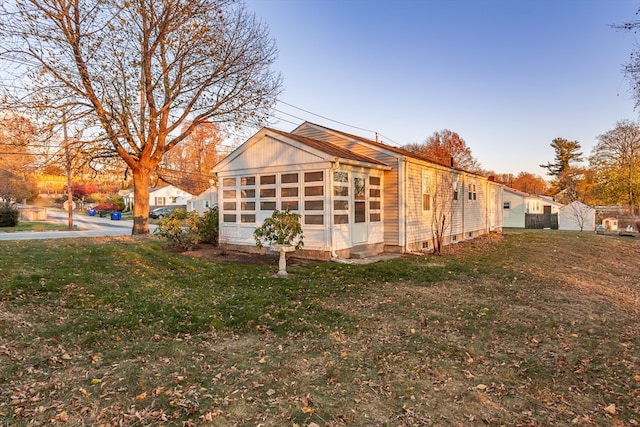 view of side of property with a lawn and a sunroom