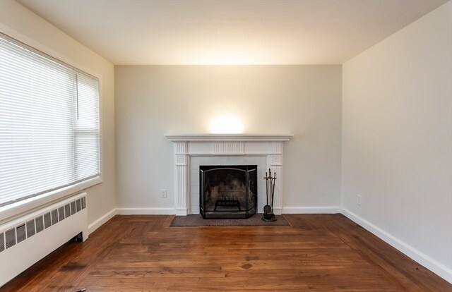 unfurnished living room with dark hardwood / wood-style floors and radiator