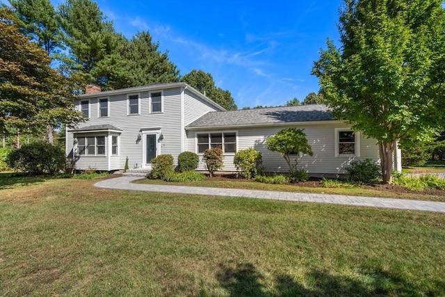 view of front of home with a chimney, a front yard, and a sunroom