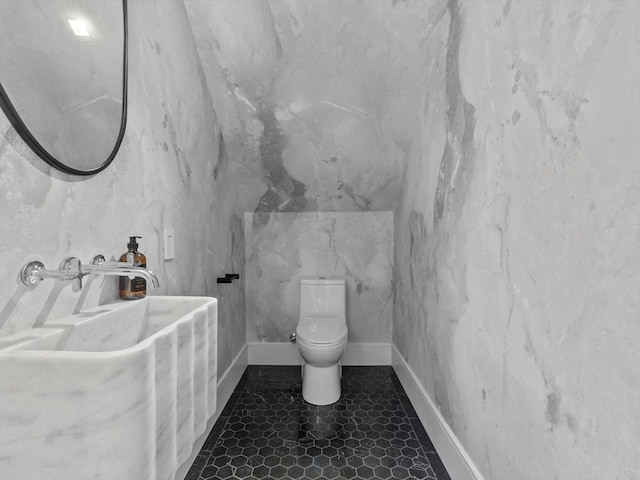 half bathroom with toilet and baseboards