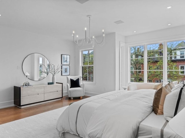 bedroom with wood finished floors, multiple windows, a chandelier, baseboards, and recessed lighting