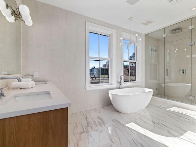 bathroom with a chandelier, a shower stall, double vanity, a freestanding bath, and marble finish floors