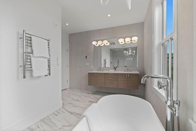 bathroom with marble finish floors, double vanity, a freestanding bath, radiator heating unit, and baseboards
