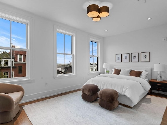 bedroom featuring wood finished floors, multiple windows, baseboards, and recessed lighting