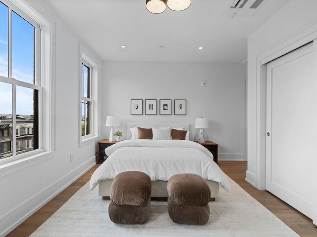 bedroom with baseboards, wood finished floors, and recessed lighting