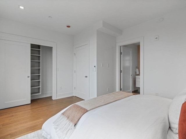 bedroom with wood finished floors, baseboards, and a closet
