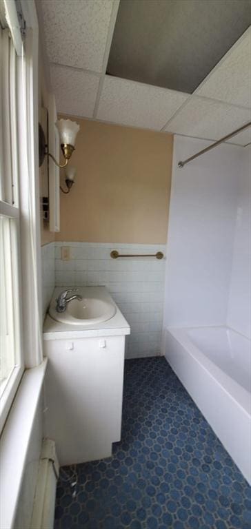 58 Jay St, North Attleboro, MA 02760 - bathroom featuring tile walls, a paneled ceiling, vanity, a baseboard heating unit, and a wainscoted wall