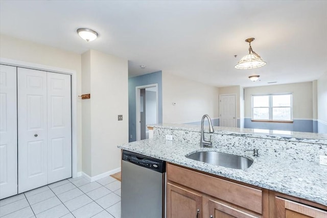 kitchen with stainless steel dishwasher, a sink, light tile patterned floors, brown cabinetry, and hanging light fixtures