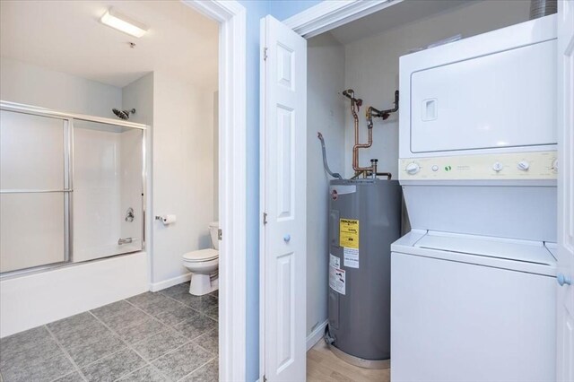 clothes washing area featuring stacked washer / dryer and water heater