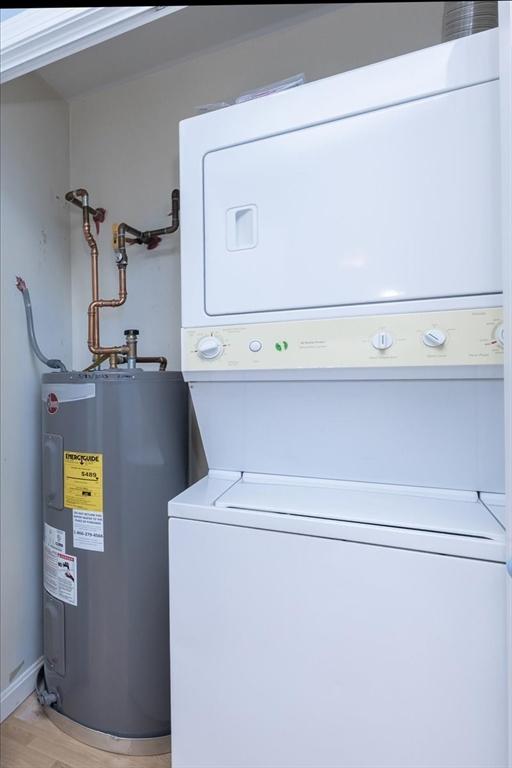 laundry room with stacked washing machine and dryer, water heater, and light wood-style flooring