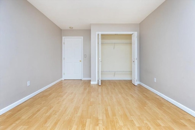 unfurnished bedroom with light wood-style flooring, baseboards, and a closet