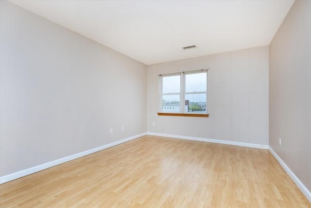 spare room featuring light wood-type flooring and baseboards