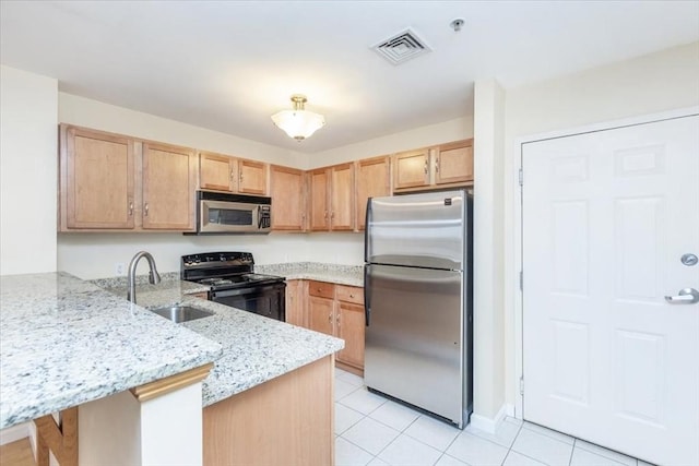 kitchen featuring appliances with stainless steel finishes, a sink, a peninsula, light stone counters, and light tile patterned floors