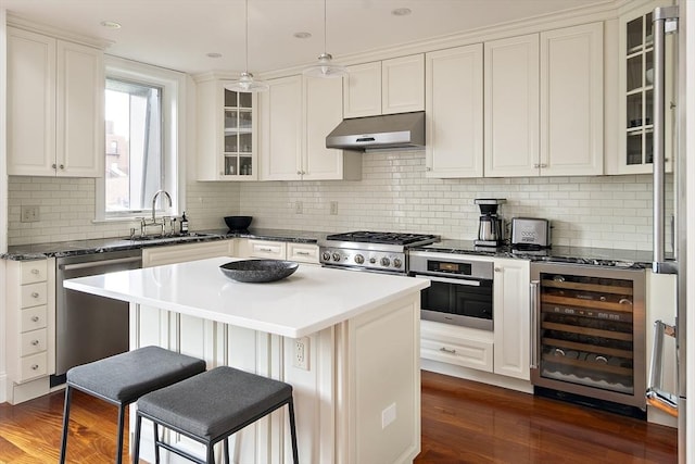 337 Marlborough Unit 3, Boston, MA 02115 - kitchen featuring under cabinet range hood, stainless steel appliances, a sink, beverage cooler, and a kitchen breakfast bar