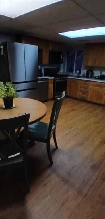 kitchen with black electric range, hardwood / wood-style floors, and stainless steel fridge