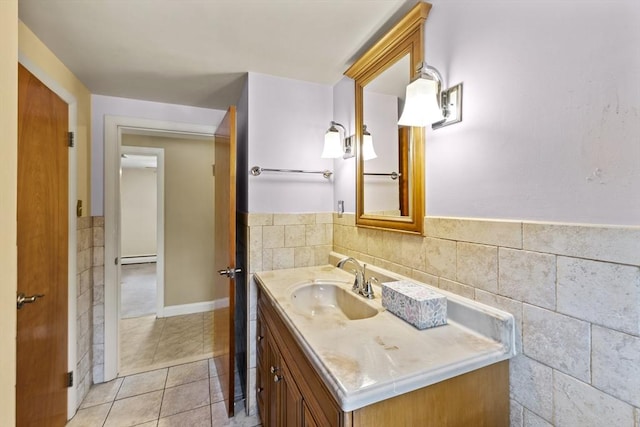 bathroom with a wainscoted wall, tile walls, baseboard heating, vanity, and tile patterned flooring