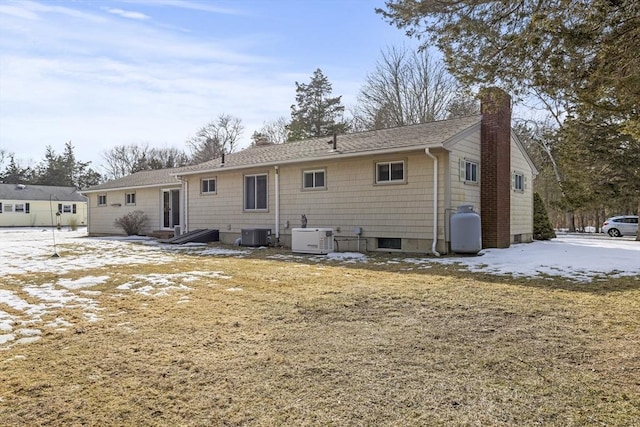 back of house with a chimney and central AC unit