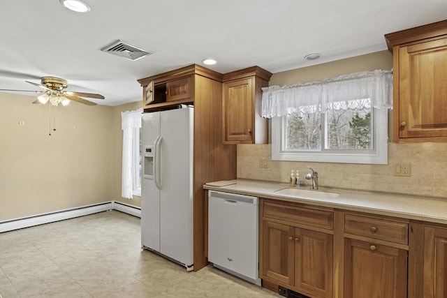 kitchen featuring white appliances, brown cabinetry, and a sink