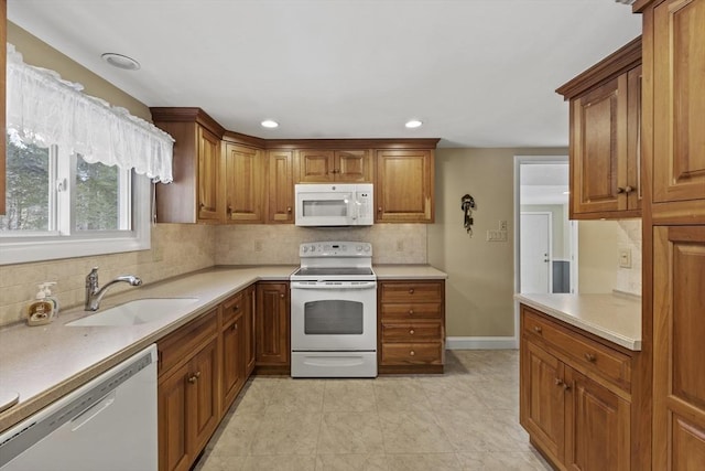 kitchen with white appliances, a sink, light countertops, backsplash, and brown cabinets