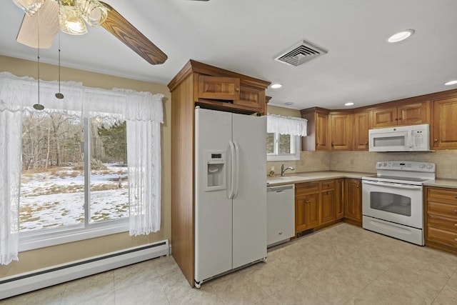 kitchen with a baseboard heating unit, light countertops, white appliances, and visible vents