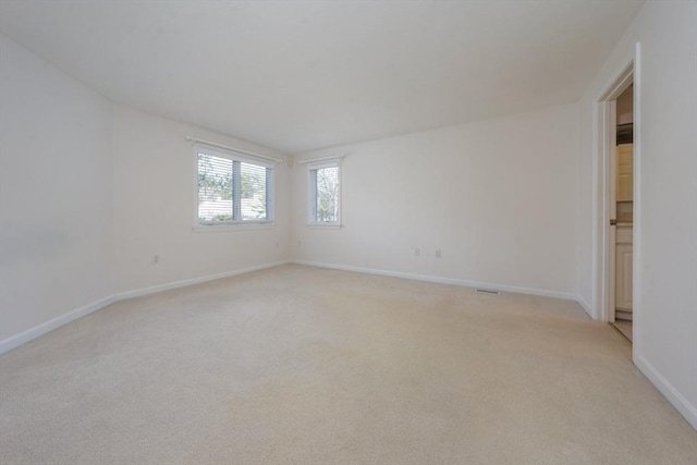 unfurnished room featuring baseboards, light carpet, and visible vents