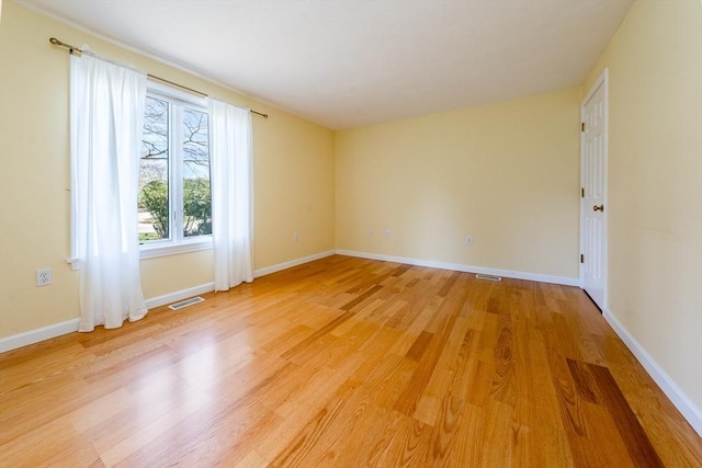 unfurnished room featuring visible vents, light wood finished floors, and baseboards