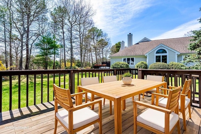 deck featuring outdoor dining area and a lawn
