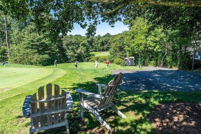 view of home's community with view of golf course and a yard