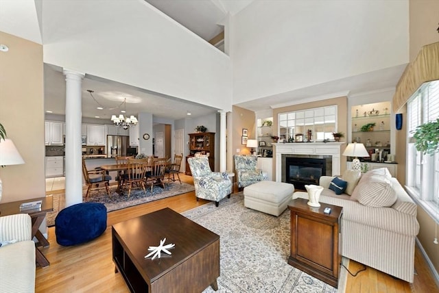 304 Godfrey Dr Unit 304, Norton, MA 02766 - living room featuring ornate columns, light wood-style flooring, a chandelier, a glass covered fireplace, and a towering ceiling