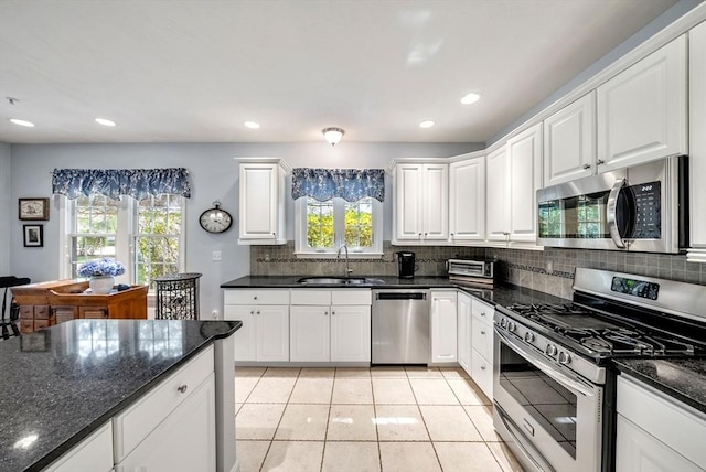 304 Godfrey Dr Unit 304, Norton, MA 02766 - kitchen featuring appliances with stainless steel finishes, a sink, decorative backsplash, light tile patterned floors, and white cabinetry