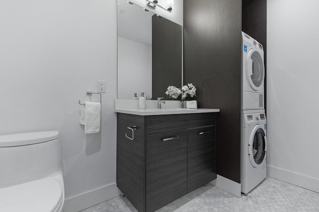 bathroom with toilet, tile patterned floors, stacked washer / dryer, and vanity